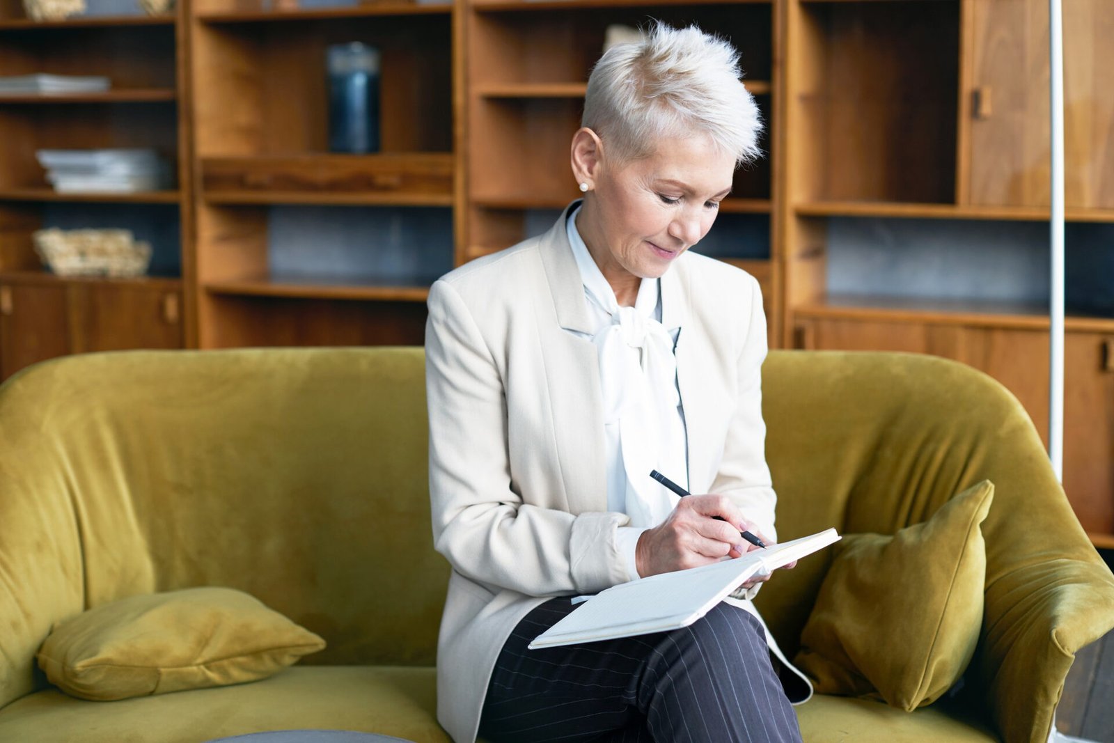 Woman journaling to turn expertise into a business, notebook sitting on a sofa
