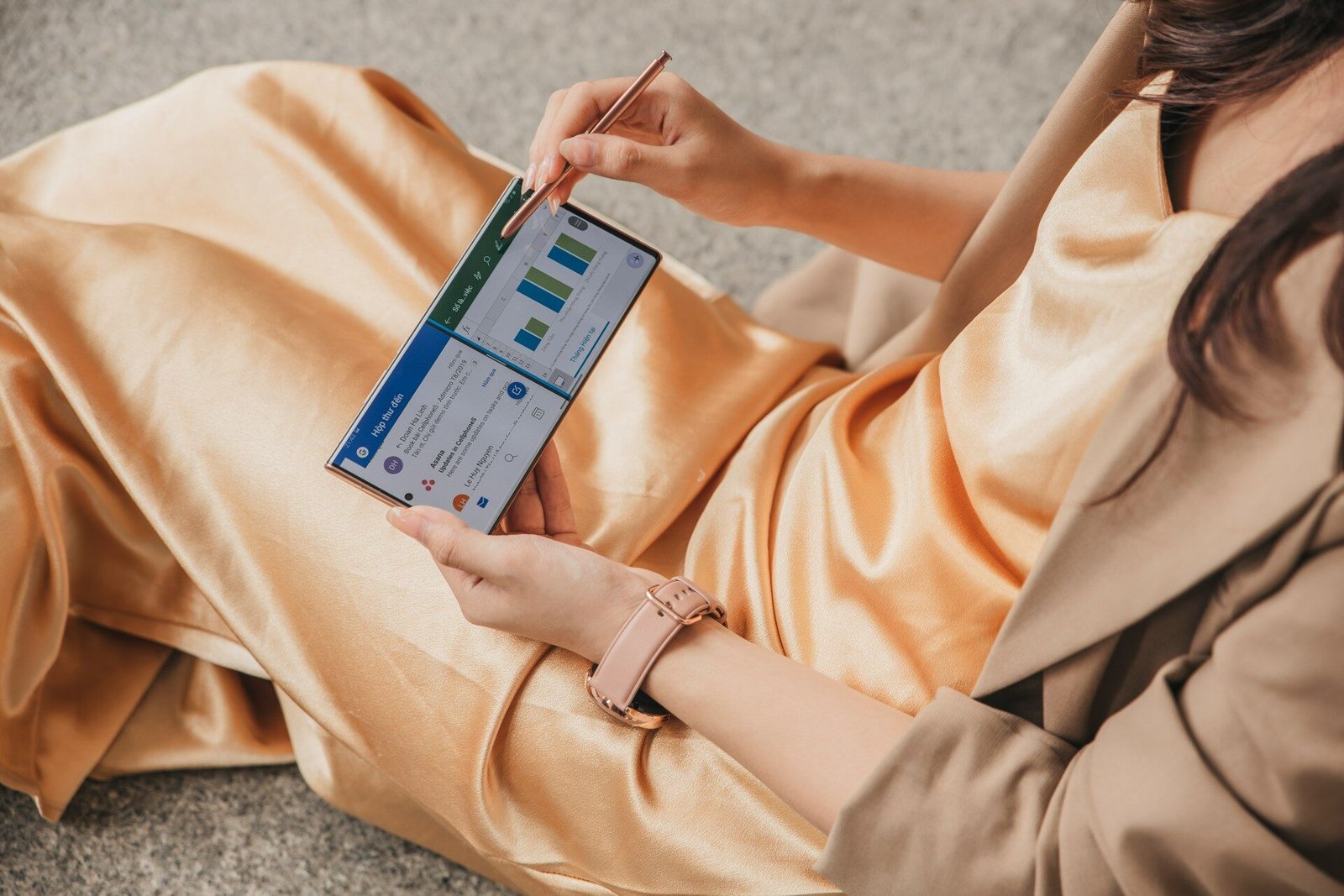 Woman reviewing what is profit for small business on a spreadsheet, in beige dress holding blue box