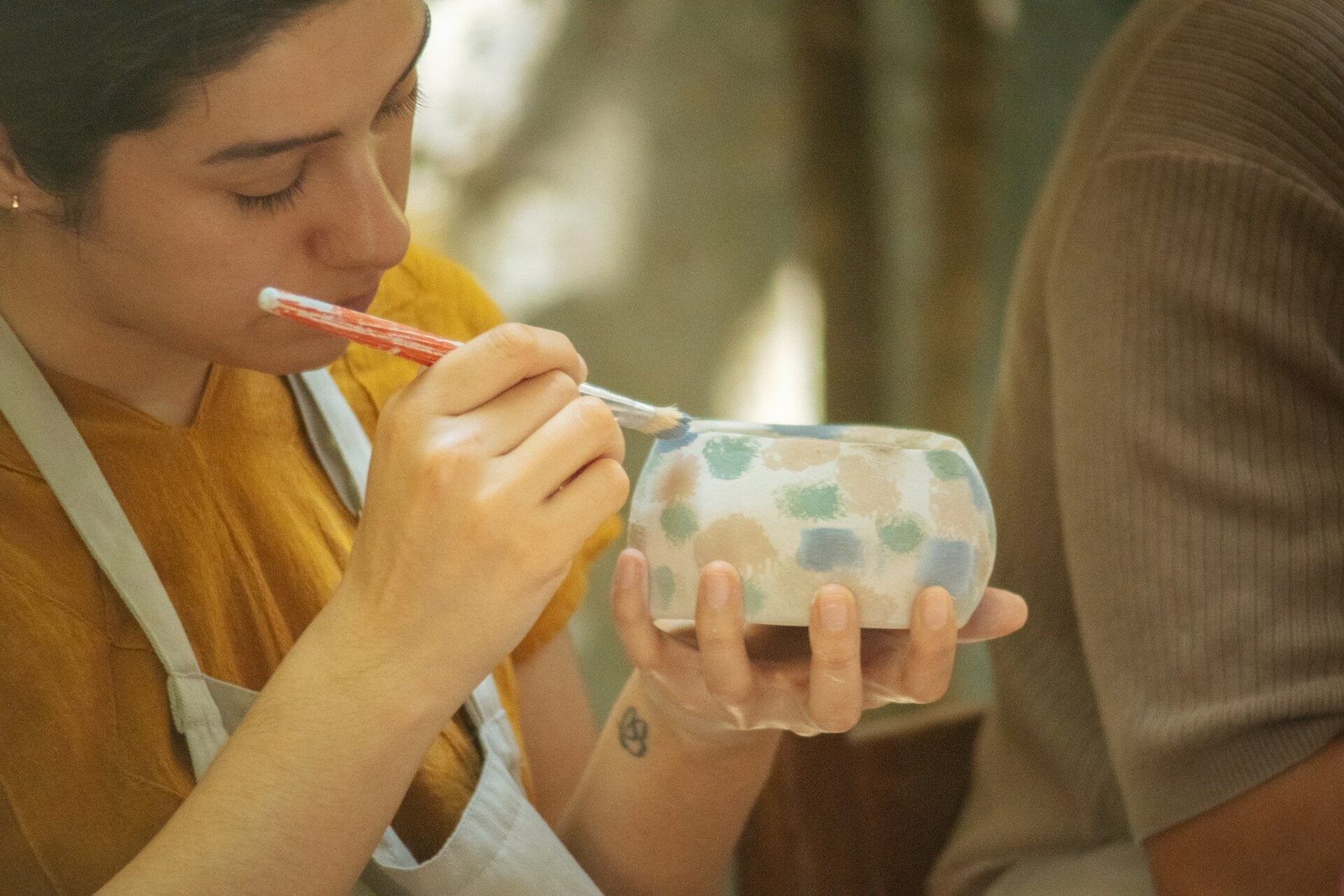 How to price handmade products. Woman painting a patterned ceramic bowl with a brush